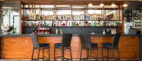 A bar area with wooden bar counters, wicker bar stools, and a variety of liquor bottles.