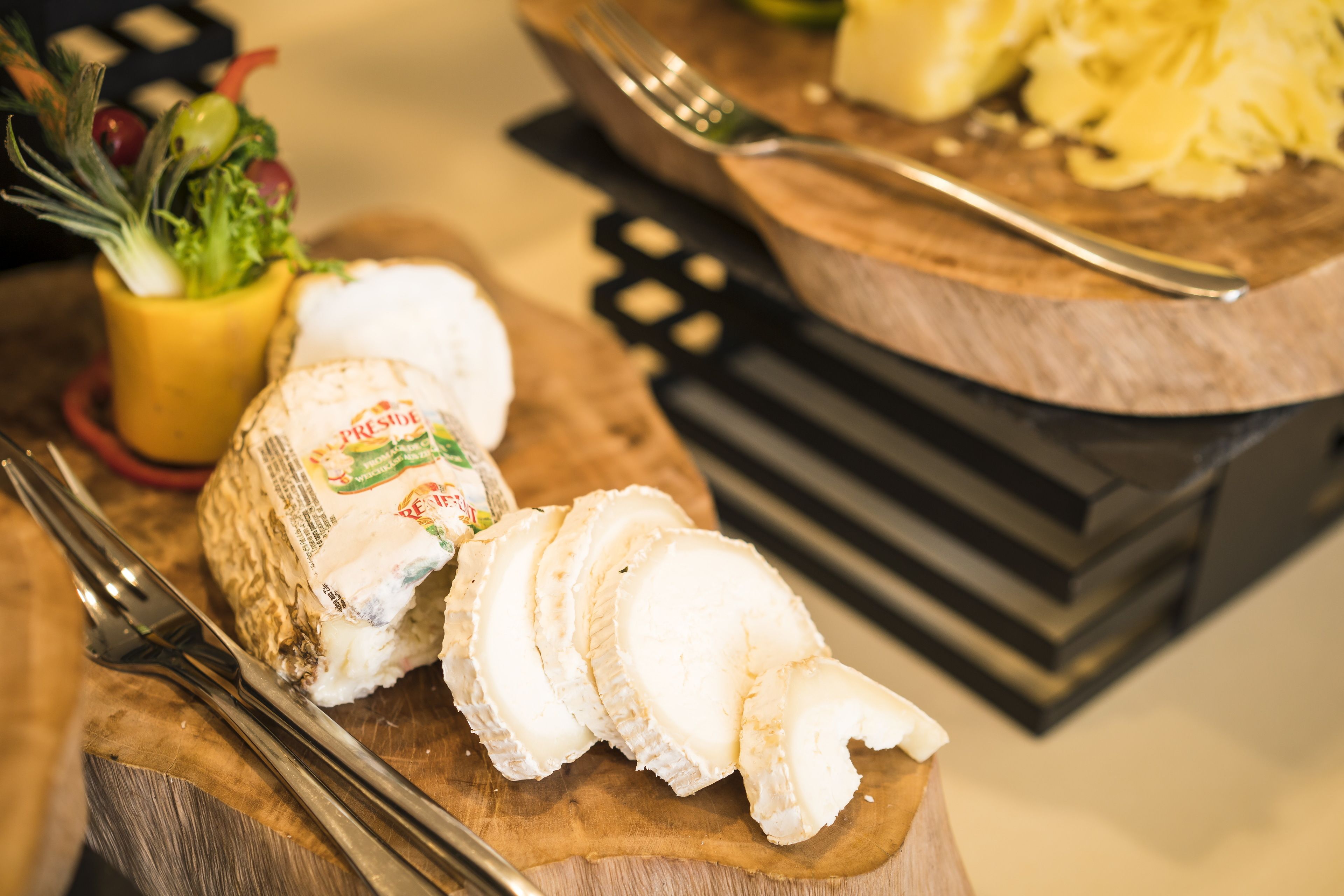 Una tabla de madera con queso en rodajas y un tenedor.