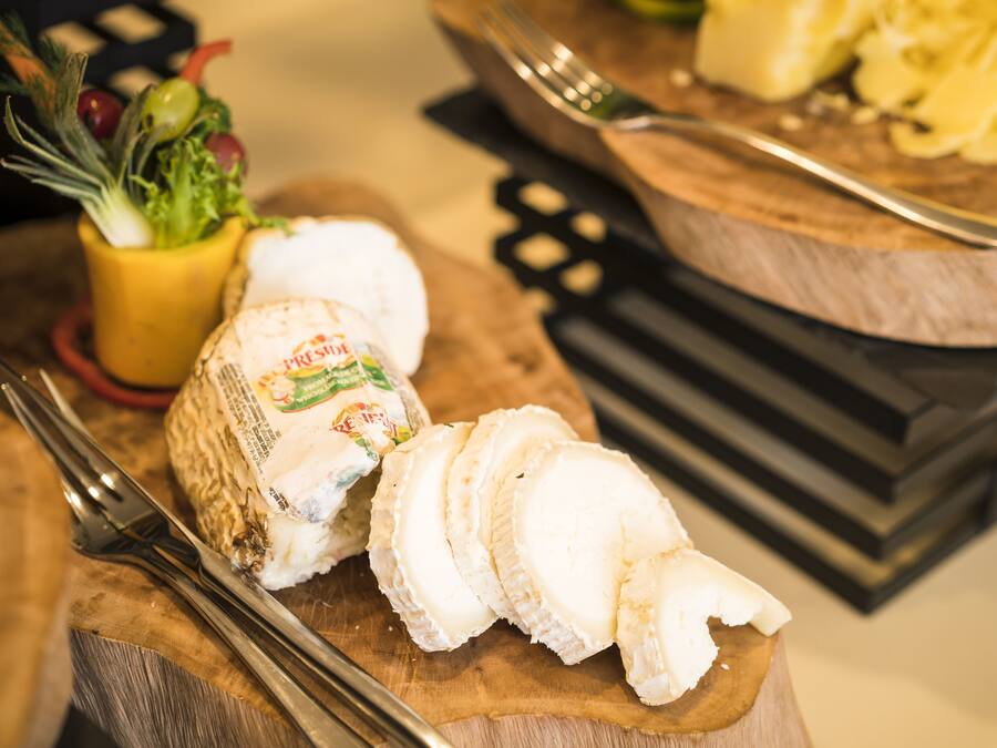Una tabla de madera con queso en rodajas y un tenedor.