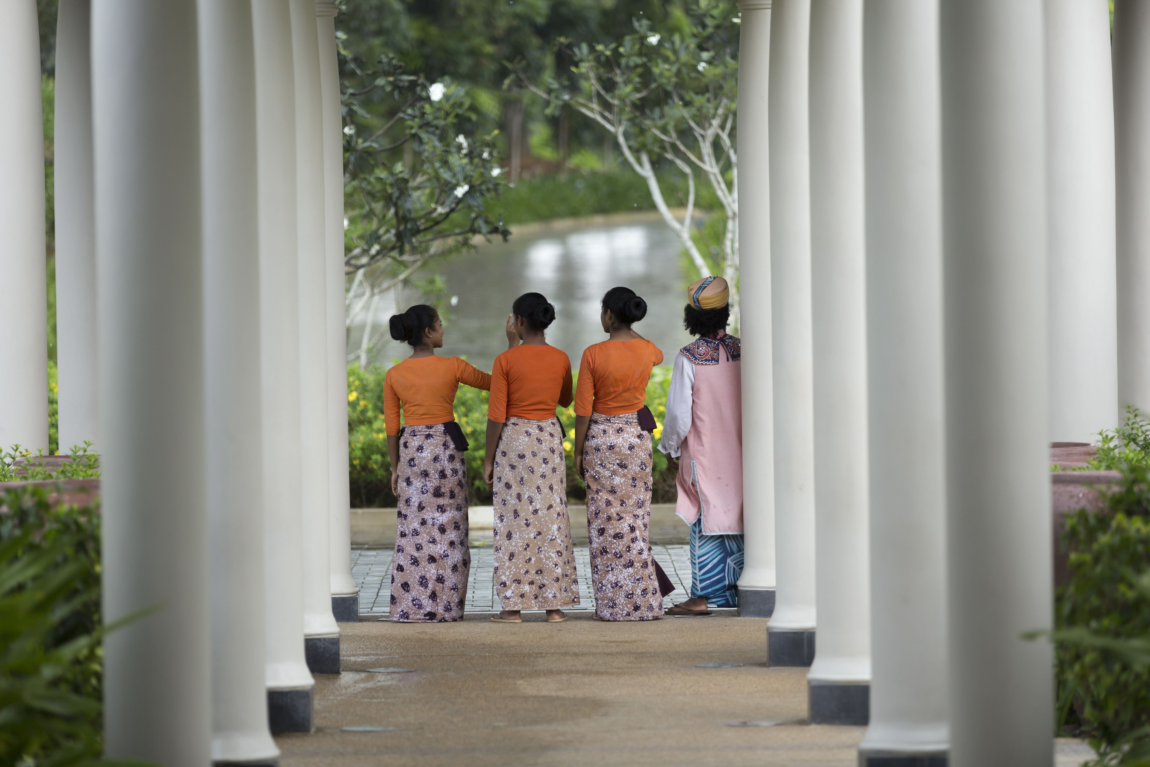 A covered walkway with white columns and a view of a body of water.