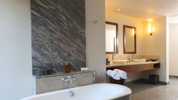 A modern bathroom with a freestanding bathtub, a marble wall, and a vanity with a sink and mirror.