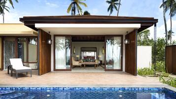 A modern poolside area with a lounge chair, a sofa set, and a view of the pool.