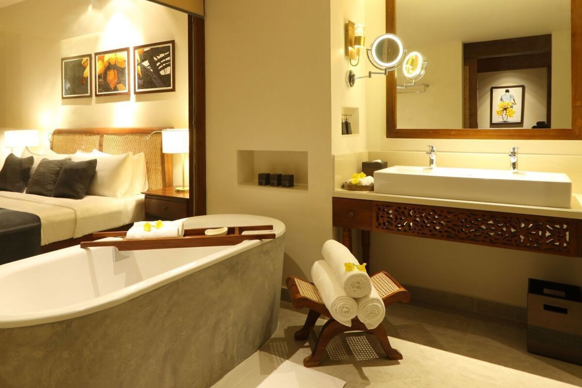 Une salle de bain moderne avec une baignoire, un grand miroir et un meuble-lavabo.