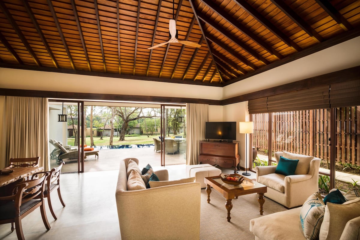 Amplia sala de estar con techo de madera, un sofá, televisión y una mesa de comedor.