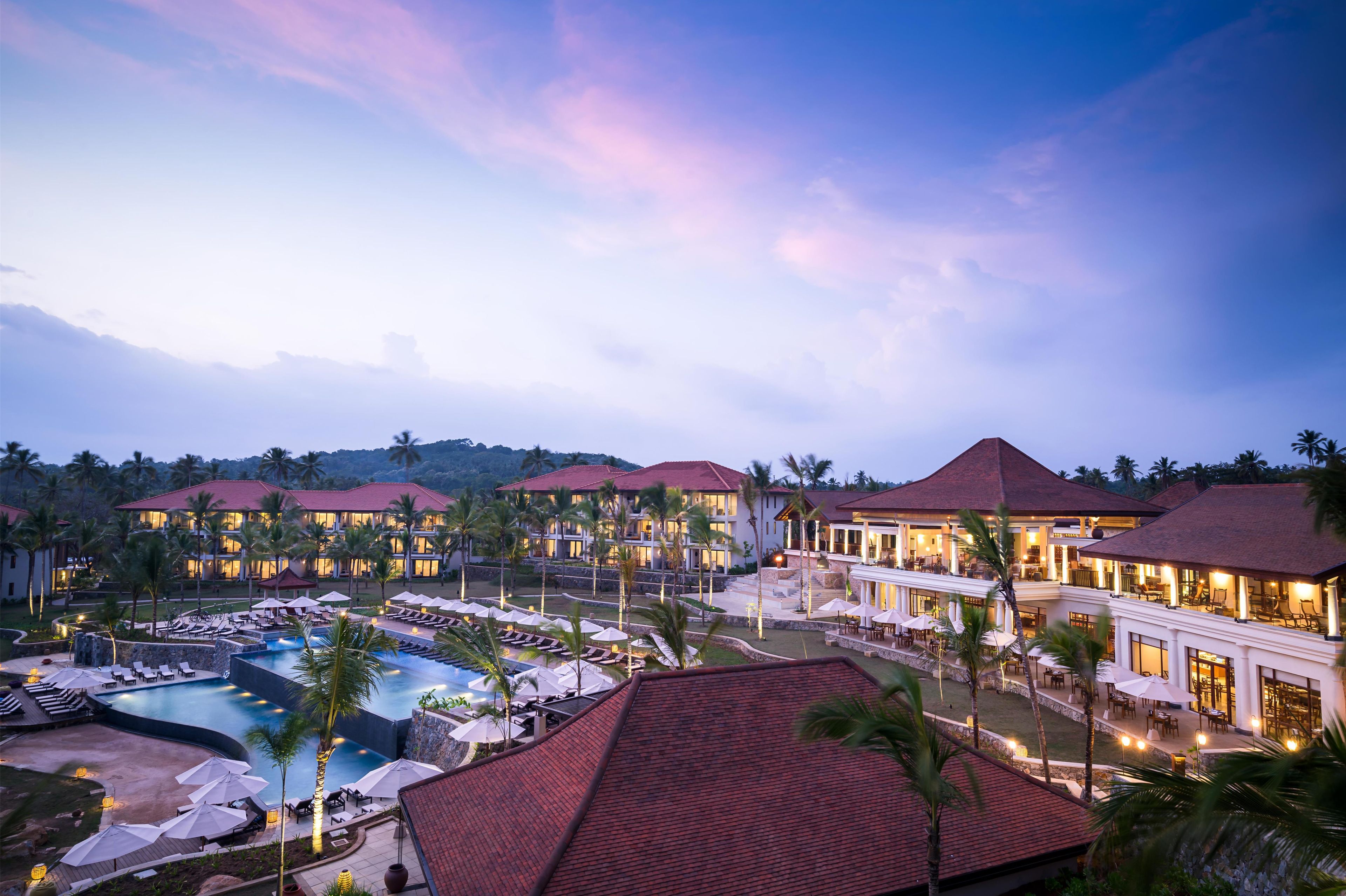 Um resort com vários edifícios, piscina e palmeiras.
