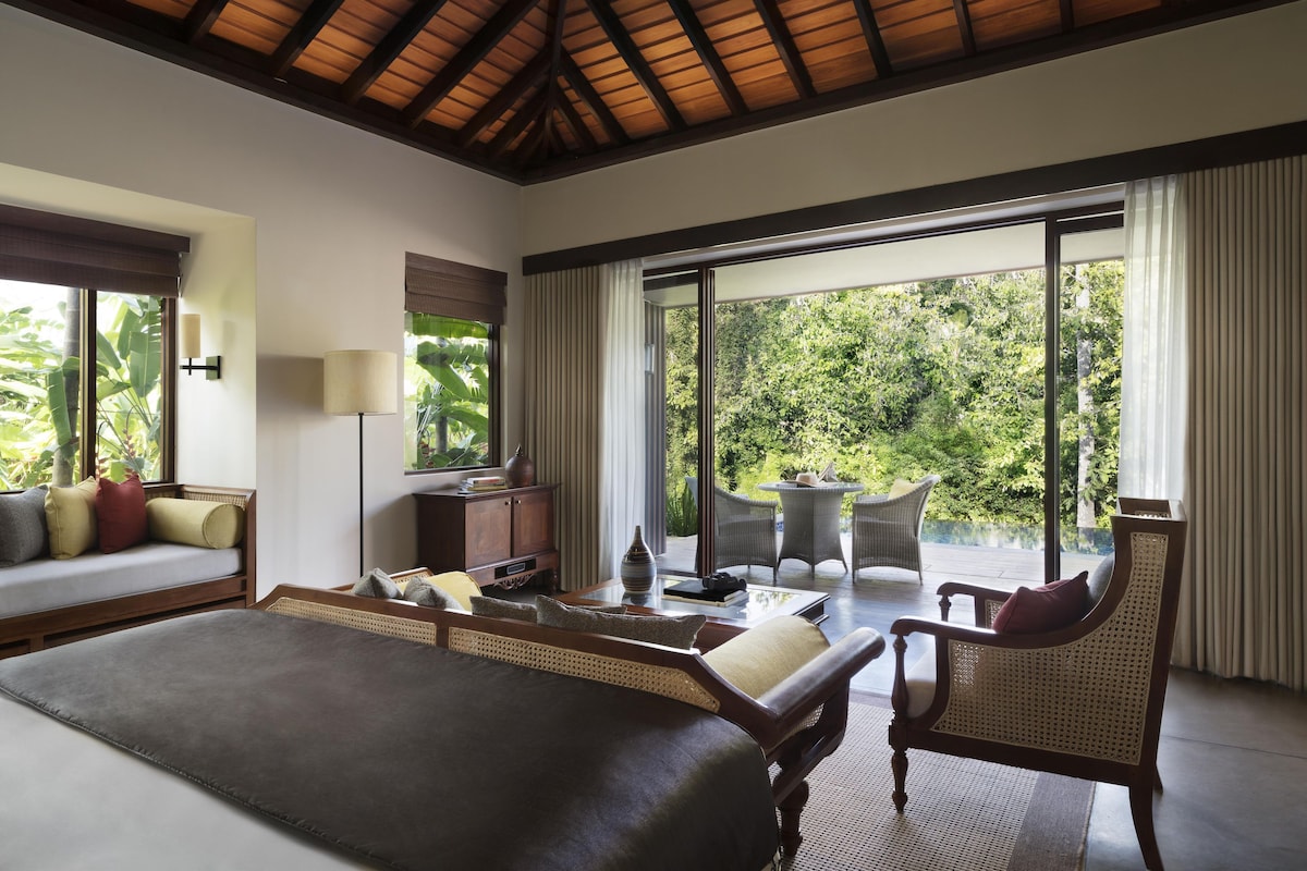 Un dormitorio con una cama grande, un escritorio, una silla y vistas al exterior.