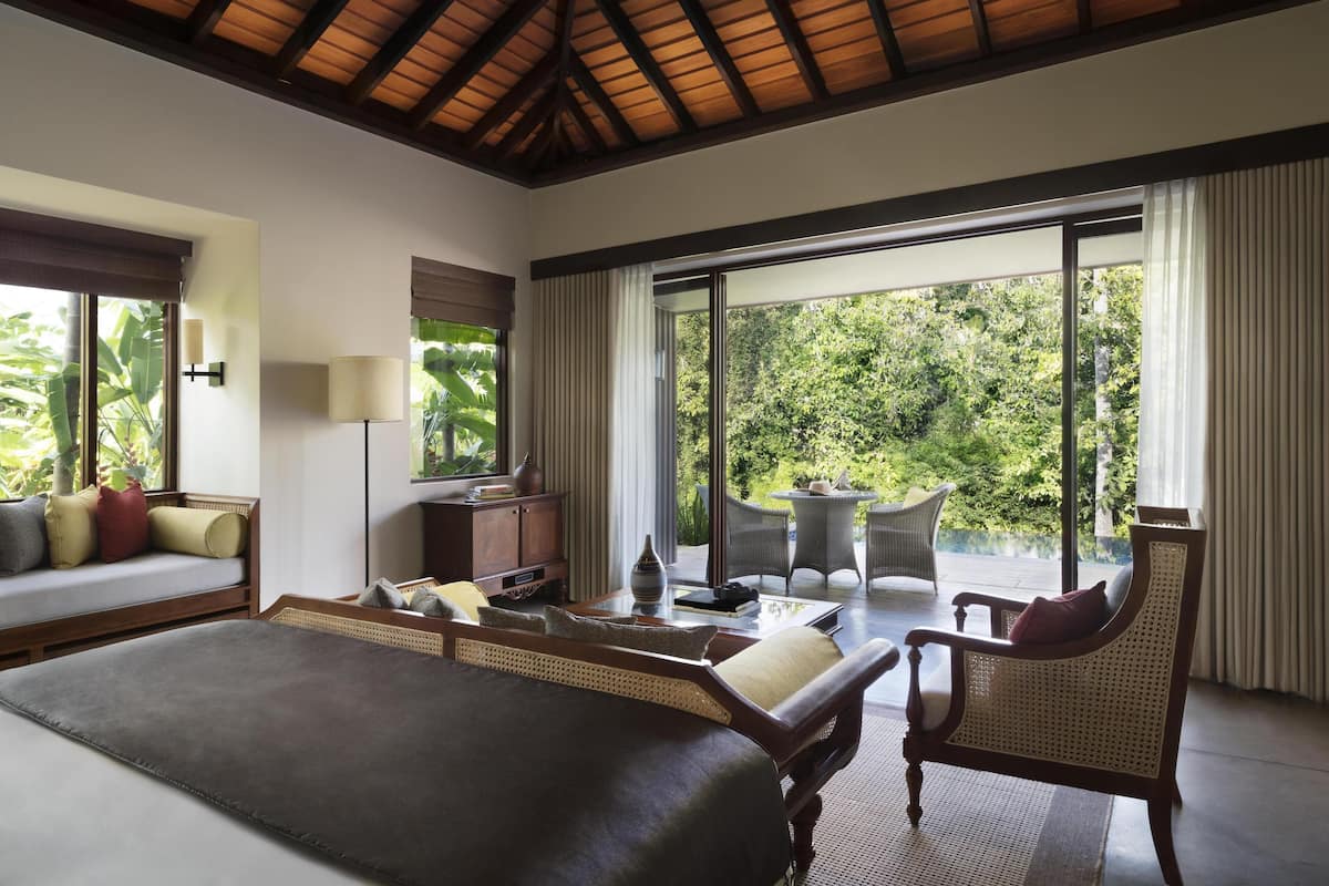 Un dormitorio con una cama grande, un escritorio, una silla y vistas al exterior.