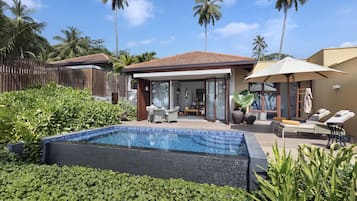 A poolside area with a lounge chair, a table, and a covered seating area.