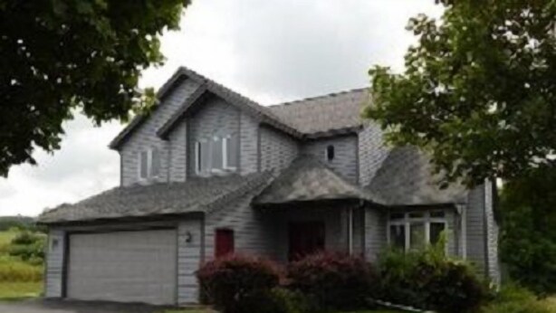 A two-story house with a garage, surrounded by greenery. - Augusta House (Galena)