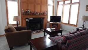 A living room with a fireplace, television, and seating area. - Augusta House (Galena)