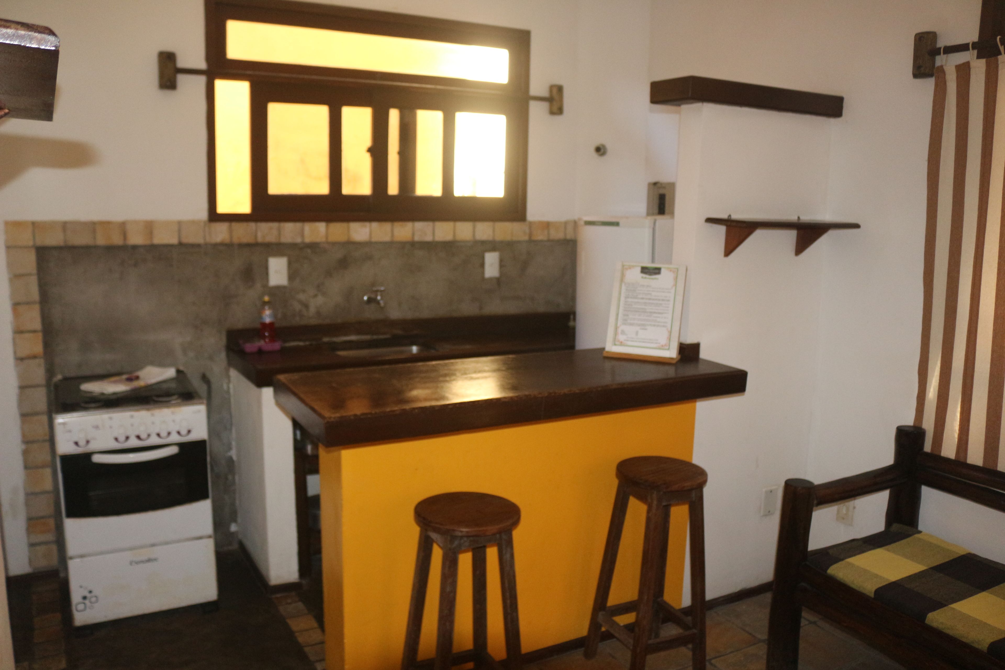 Une cuisine compacte dotée d’un four encastré, d’un évier et d’un coin bar avec des tabourets.