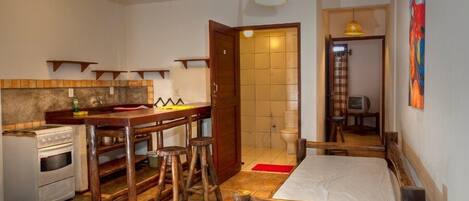 A compact kitchen with a stove, stools, and a dining area.