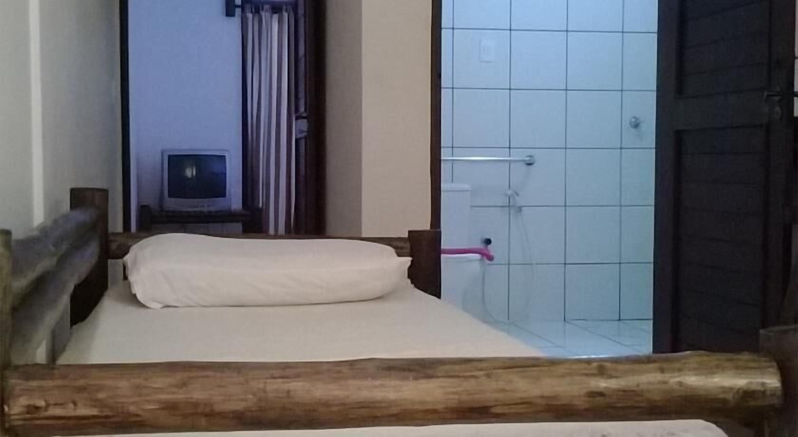 Un letto singolo con un poggiatesta in legno, un cuscino bianco e una panca in legno ai piedi del letto.
