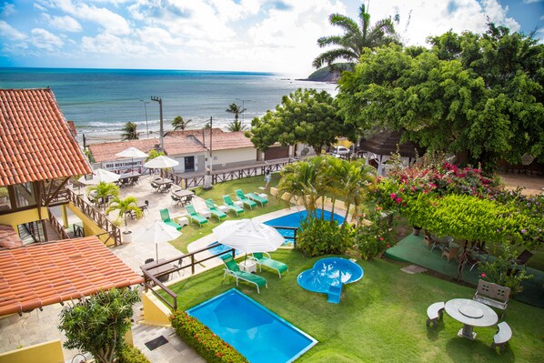 A pool area with a clear view of the ocean, surrounded by lush greenery and outdoor seating. - Moriah Natal Beach Hotel (Natal)