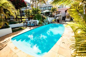 A swimming pool surrounded by palm trees and outdoor seating areas. - Moriah Natal Beach Hotel (Natal)
