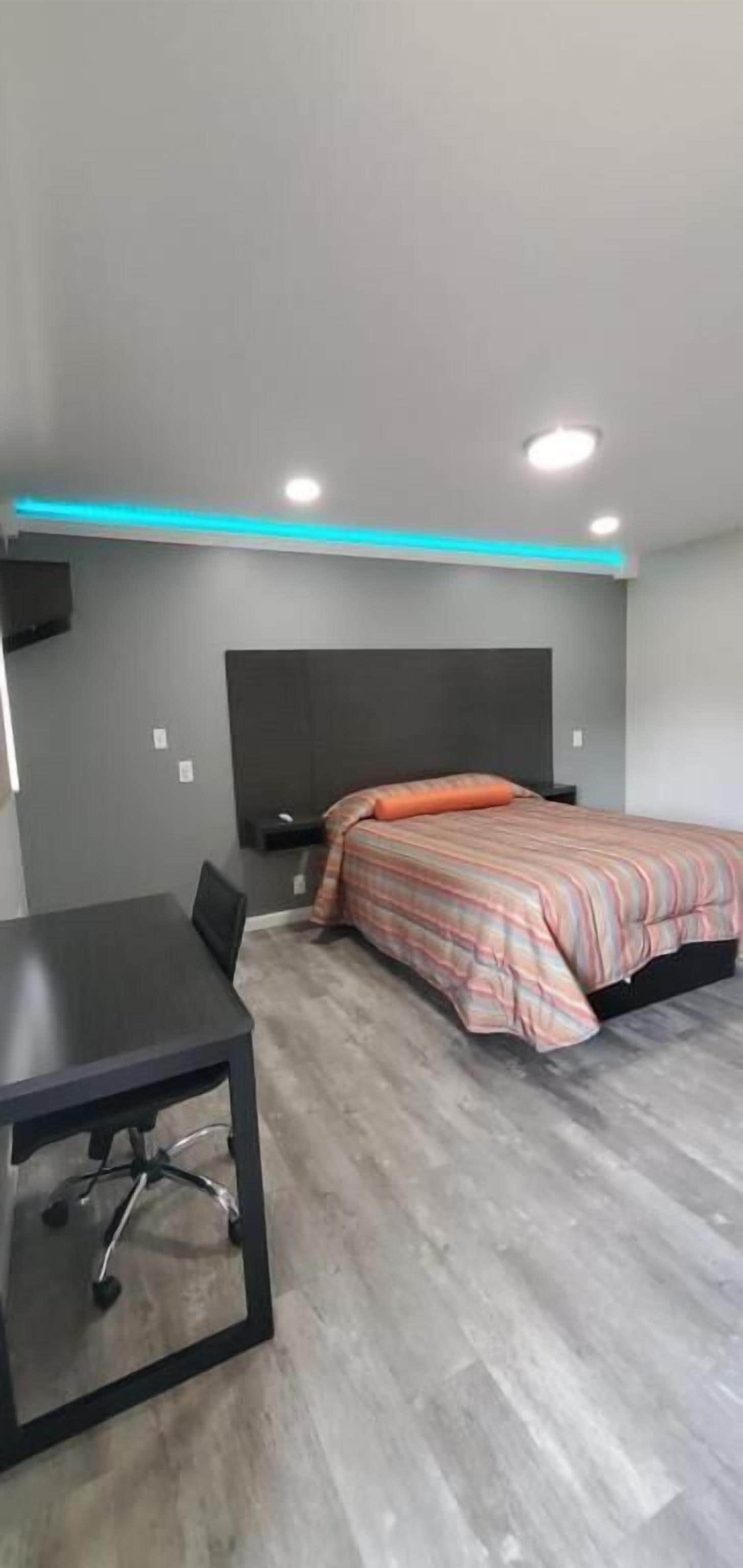 A bedroom with a bed, a desk, and a chair.