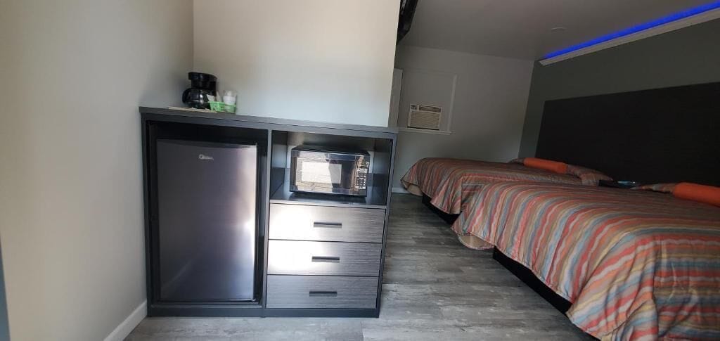 Een slaapkamer met een bed, een ingebouwd bureau met een magnetron en een kleine koelkast.