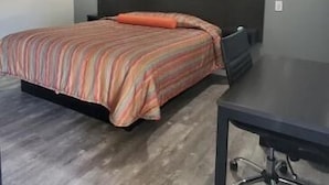 A bedroom with a bed, a desk, and a headboard. - Villa Rosa Motel (Painesville)
