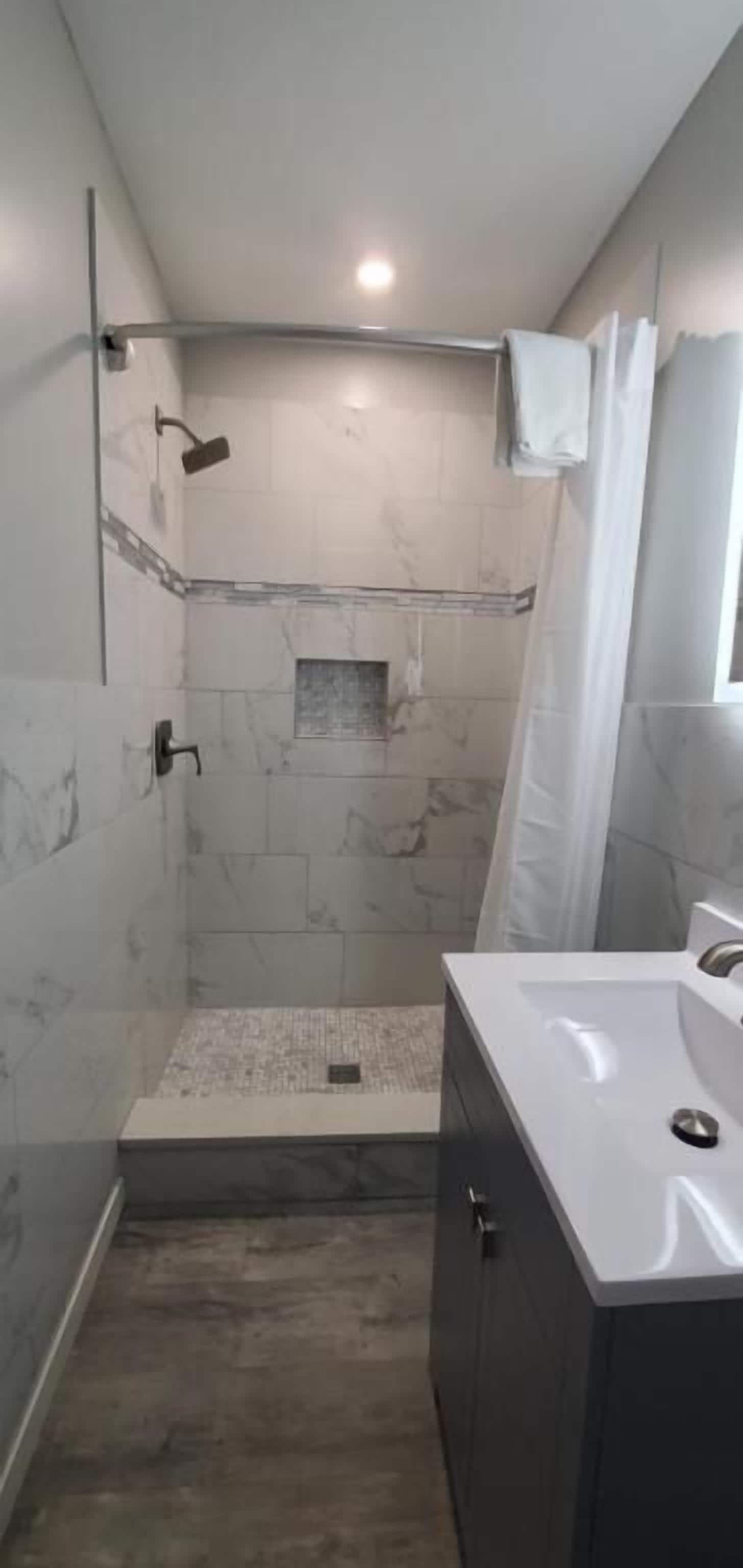 Un baño moderno con ducha, lavamanos y espejo.