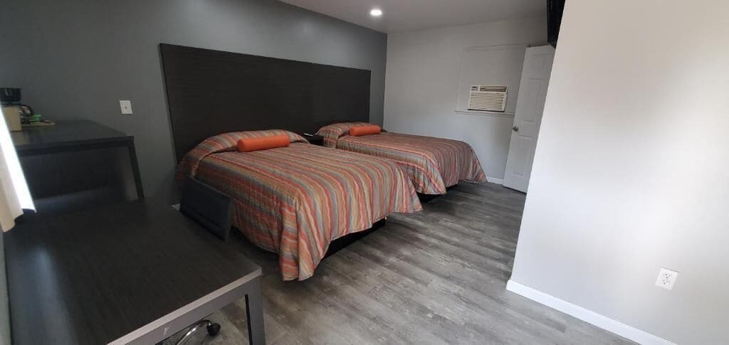 A room with two beds, a desk, and a door.