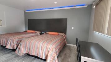 Un dormitorio con dos camas, un escritorio y un ventanal con cortinas.