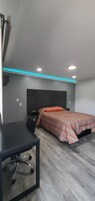 A bedroom with a bed, a desk, and a chair.
