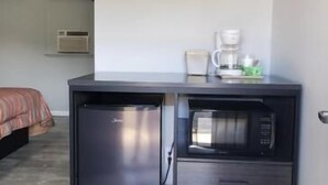 A compact kitchenette with a refrigerator, microwave, and coffee maker.