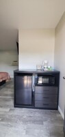 Una kitchenette compacta con refrigerador, microondas y cafetera.
