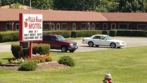 A Villa Rosa Motel sign with a red and white color scheme, indicating it is open 24 hours daily, weekly rates, and has a cablephone and heat air.