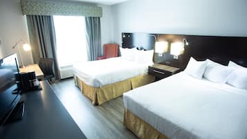 A hotel room with two beds, a desk with a computer, a chair, and a window with curtains.