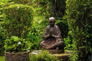 A statue of a seated figure in a garden setting. - Hotel Isla Verde (Boquete)