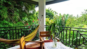 A wooden chair and table on a balcony with a view of lush greenery. - Hotel Isla Verde (Boquete)