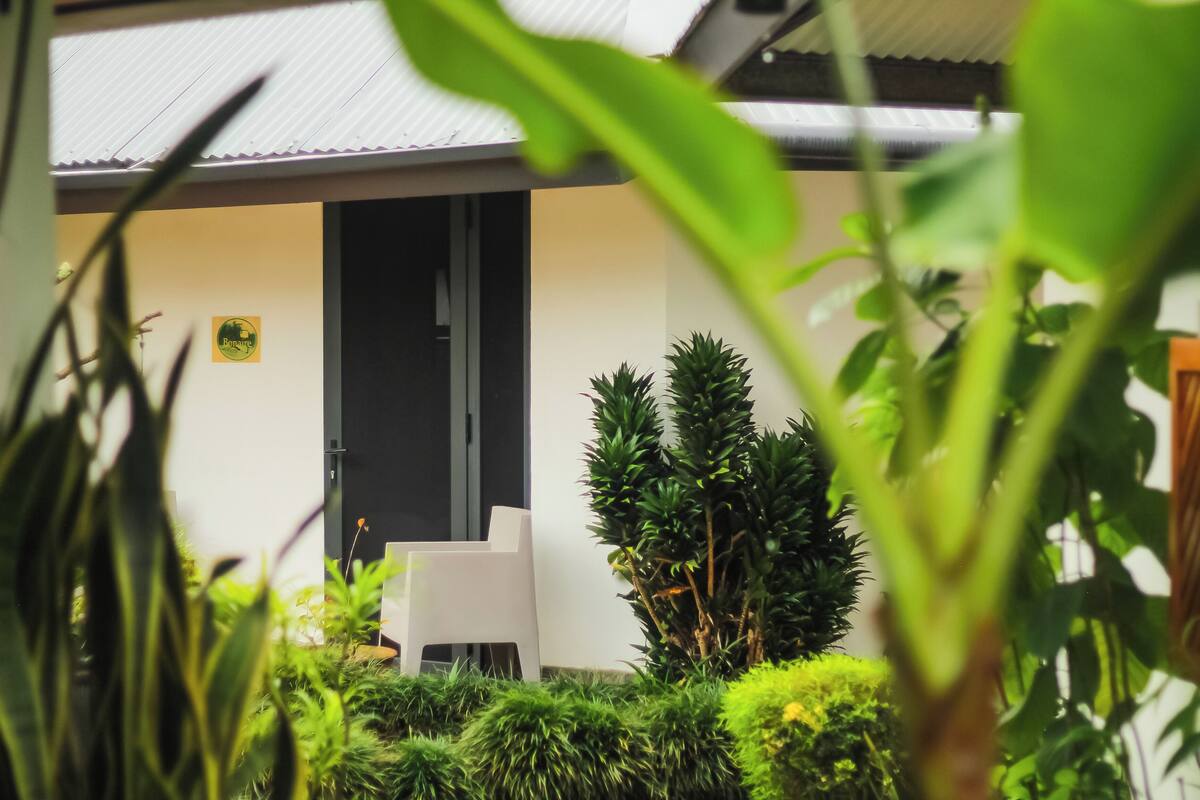 A modern outdoor seating area with a white chair and a door leading to a building.