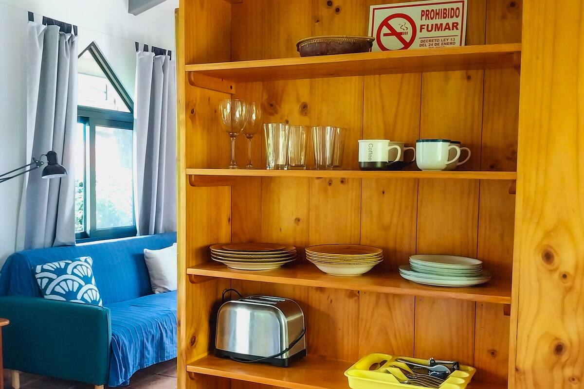 A wooden shelf unit with various kitchenware, a toaster, and a coffee maker.