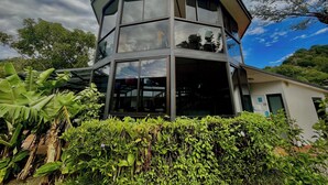 A modern, multi-level glass building with a unique octagonal shape, surrounded by lush greenery. - Hotel Isla Verde (Boquete)