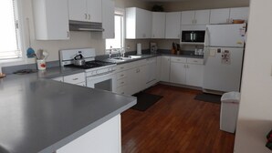 A modern kitchen with white cabinets, stainless steel appliances, and a grey countertop. - House on Pond Court (Galena)