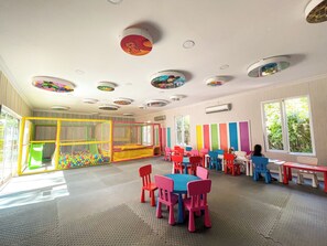 A play area with colorful play structures and a seating area with tables and chairs.