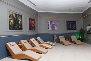 Ein Zimmer mit sechs Liegestühlen, einer Buddha-Statue und drei großen Buddha-Gemälden an der Wand.