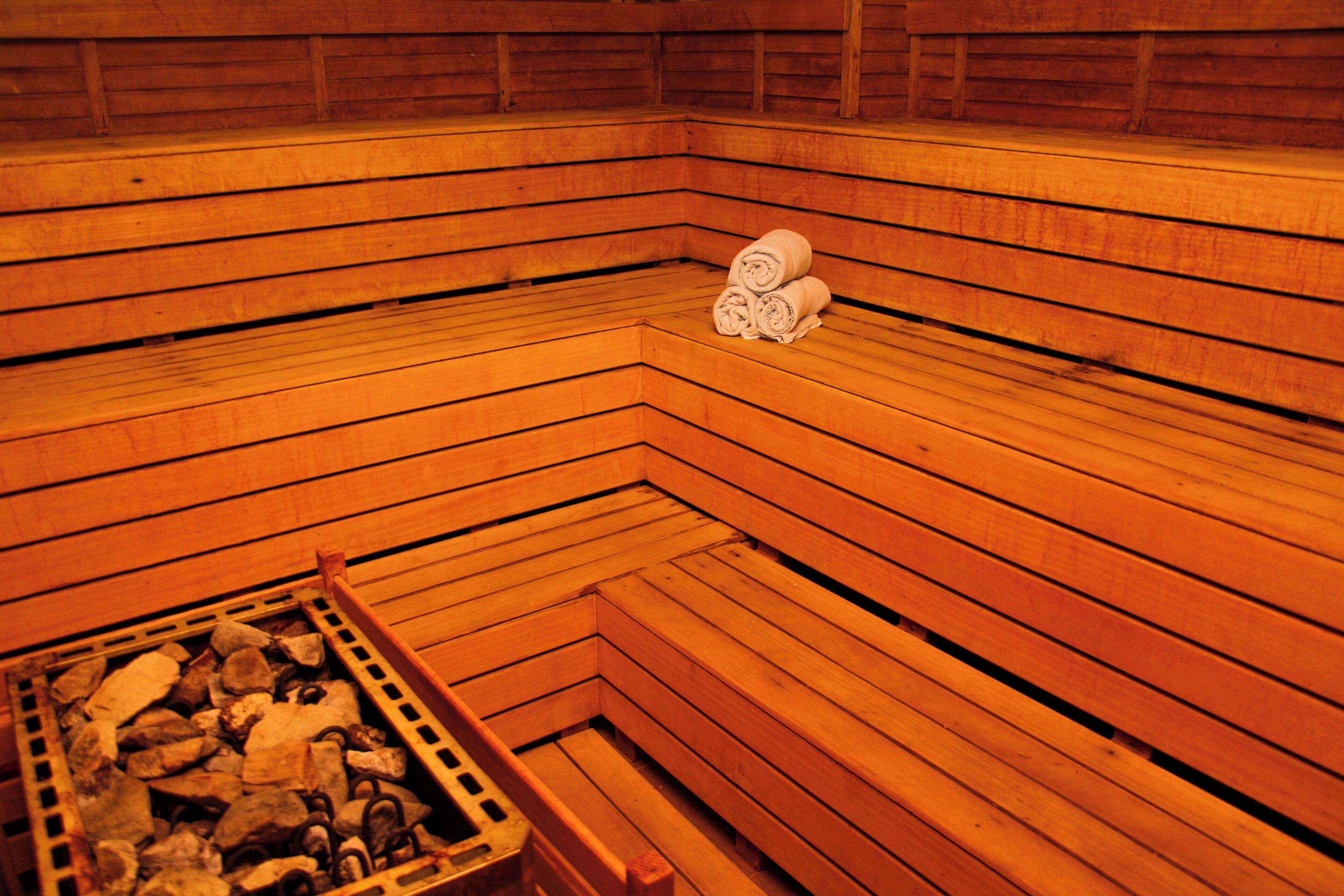 A wooden sauna with benches and a pile of rocks.