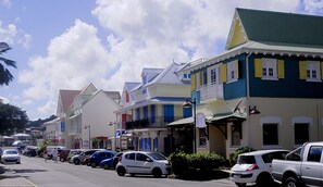 A street lined with colorful buildings, parked cars, and a clear sky. - Residence Villas Melissa (Trois-Ilets)
