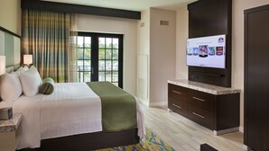 Ein Hotelzimmer mit einem Bett, einem Fernseher, einem Schreibtisch und einem Fenster mit Vorhängen.