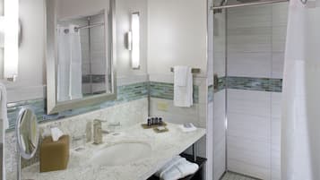 A bathroom with a sink, mirror, towel rack, and shower area.