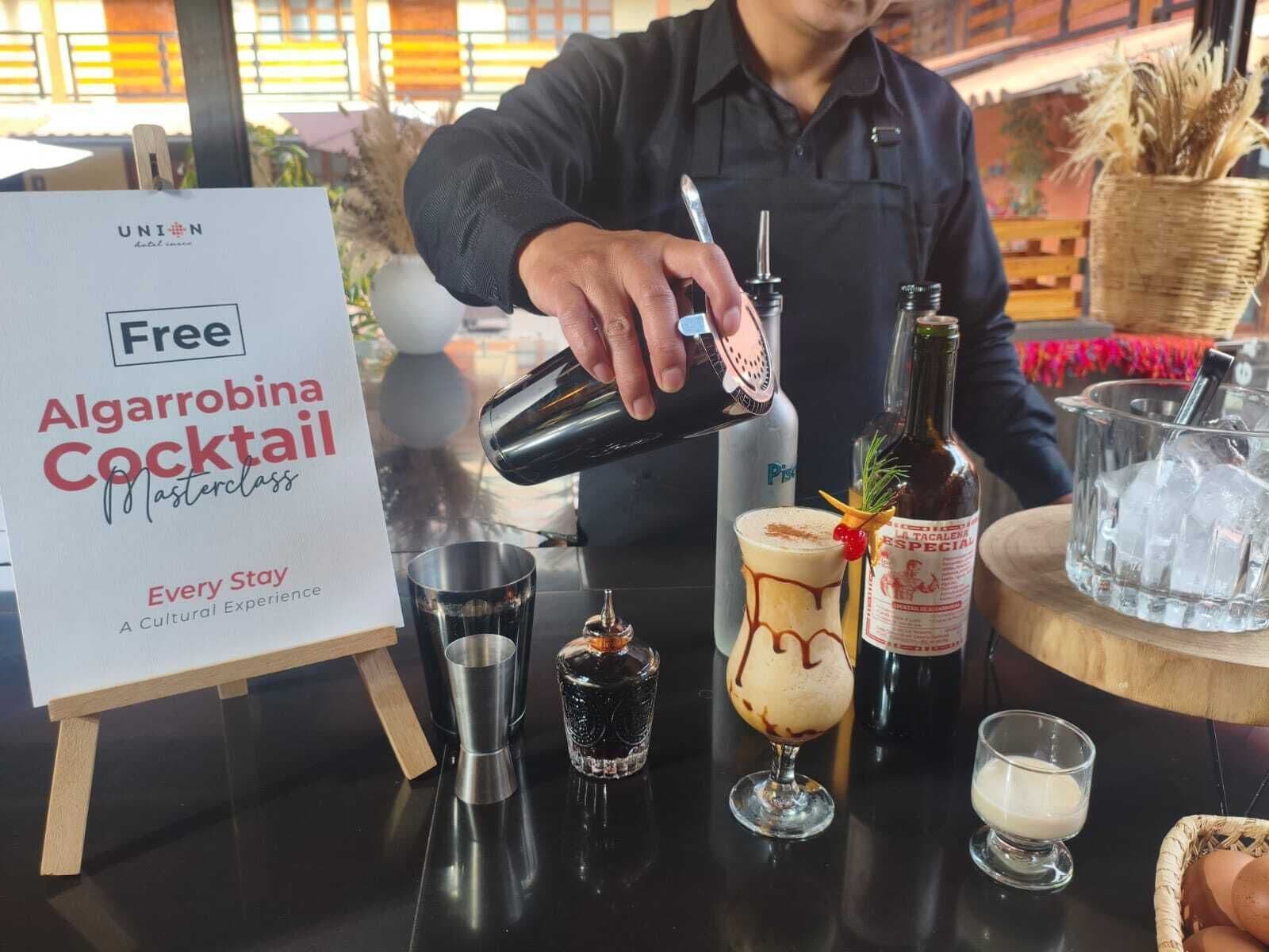 A bartender preparing a cocktail, with a sign offering a free drink, and various bar tools and ingredients on the counter.