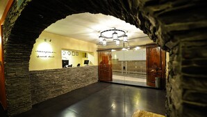 Una zona de recepción con pared de piedra, mostrador de recepción y una araña.