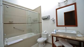 A modern bathroom with a glass-enclosed shower, a white toilet, a sink with a mirror, and a towel rack.