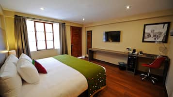 A hotel room with a bed, a desk, a chair, a TV, and a picture on the wall.