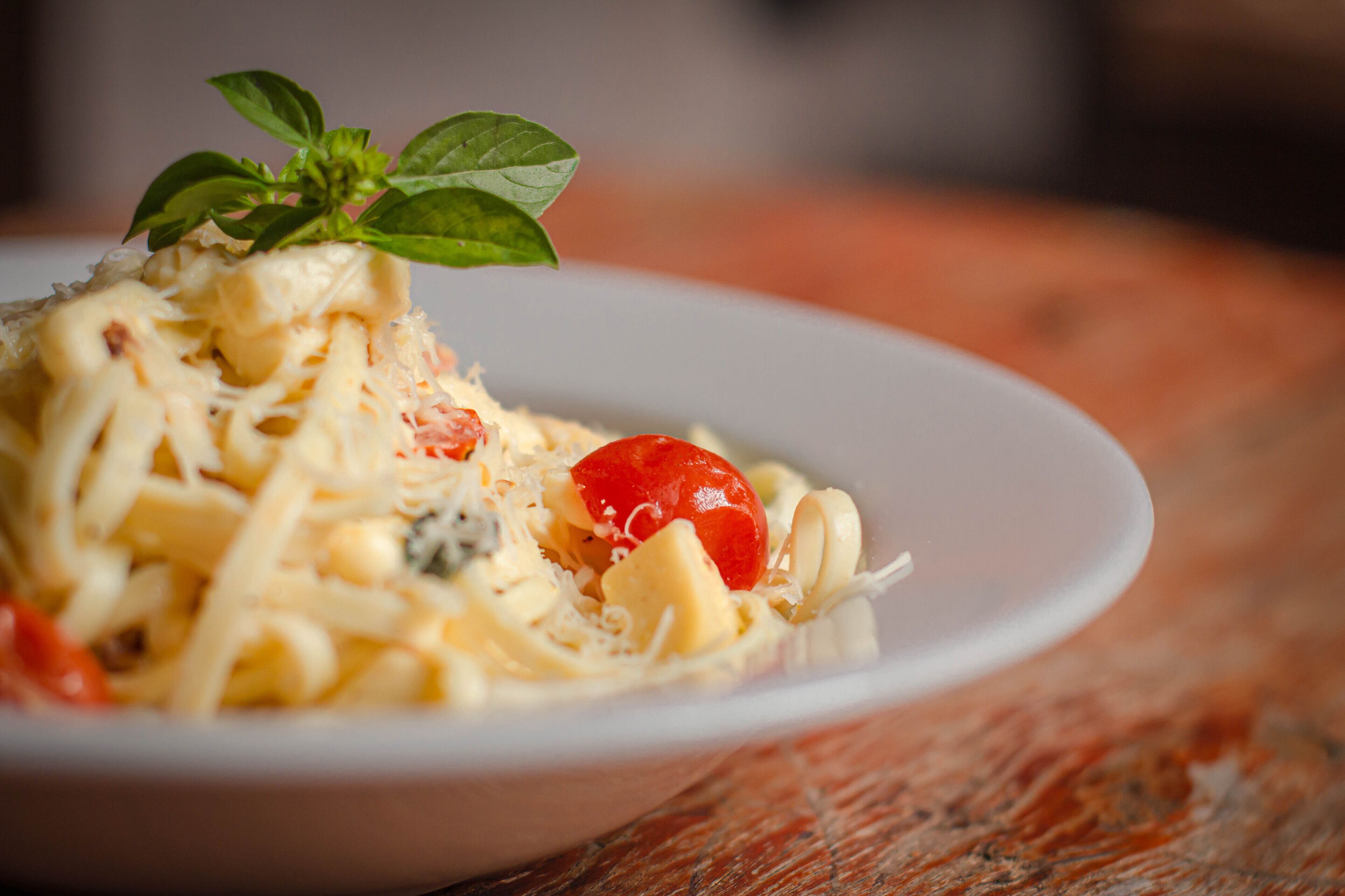 A plate of pasta with cheese and a cherry tomato garnish.