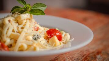 A plate of pasta with cheese and a cherry tomato garnish.