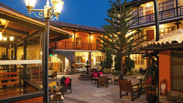 Un patio al aire libre con mobiliario, una fuente y un árbol grande.