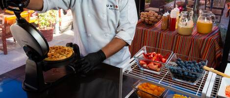 A chef preparing food at a breakfast cooking show with a variety of fruits and beverages on display.